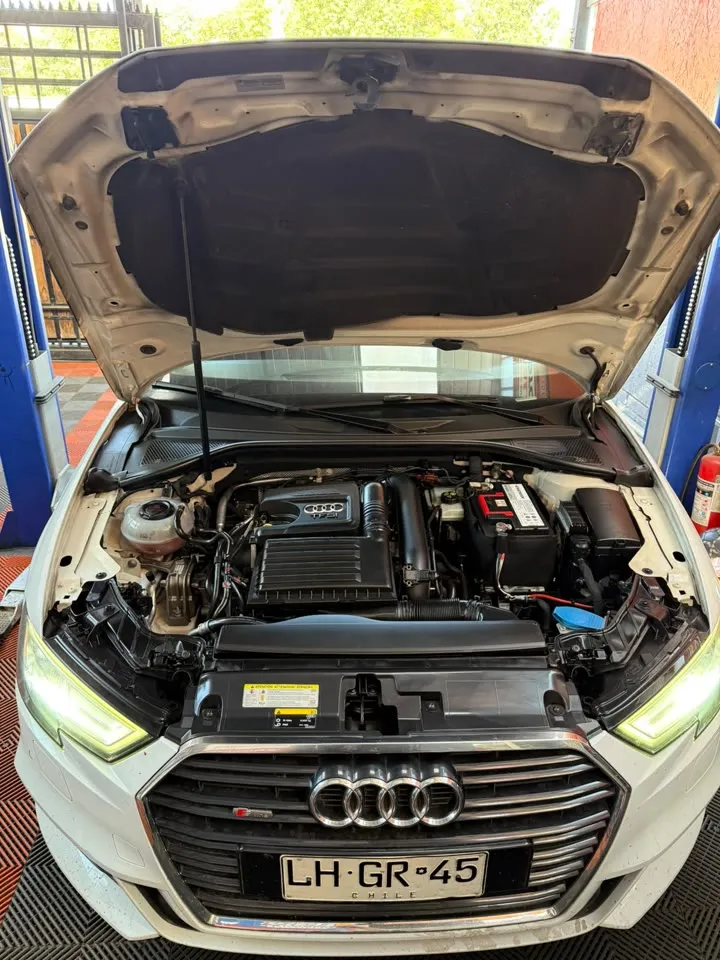 Motor de un Audi blanco con el capó abierto, visto de frente