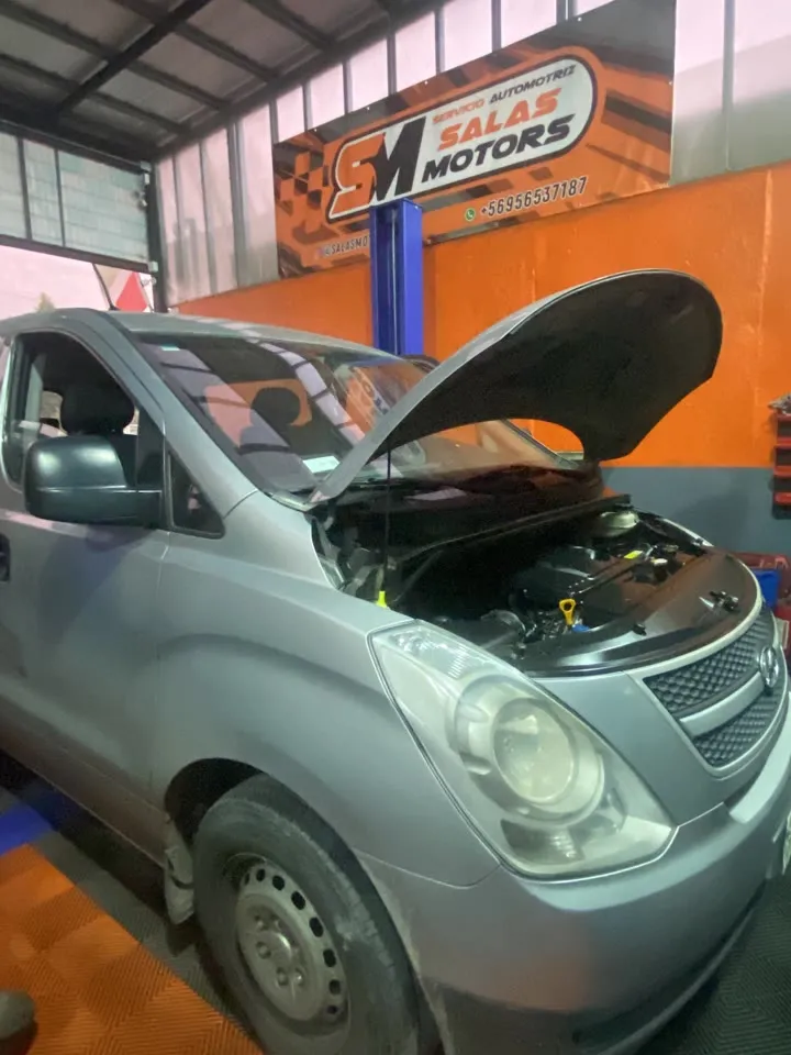 Furgón Hyundai H-1 gris con el capó abierto en el taller