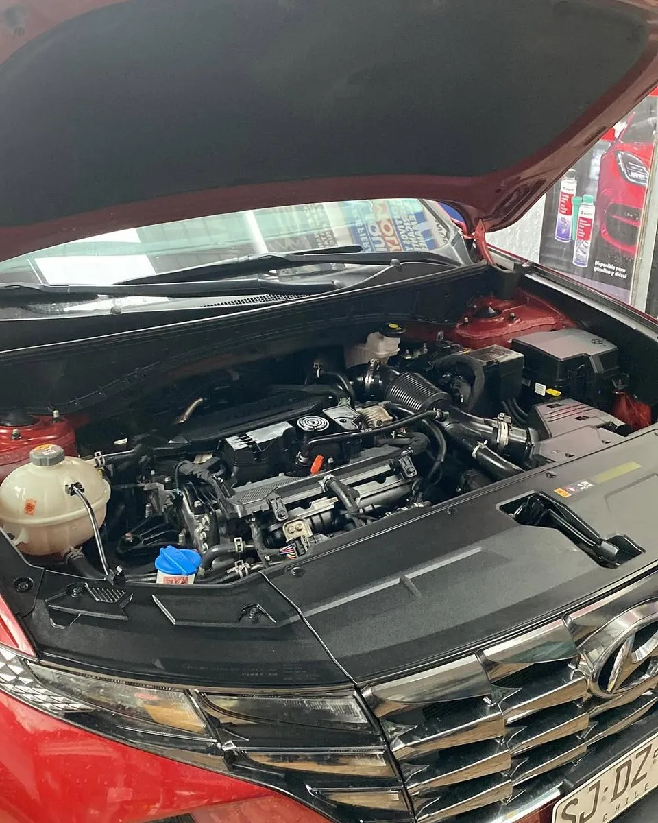 Motor de un Hyundai rojo con el capó abierto, antes de la mantención