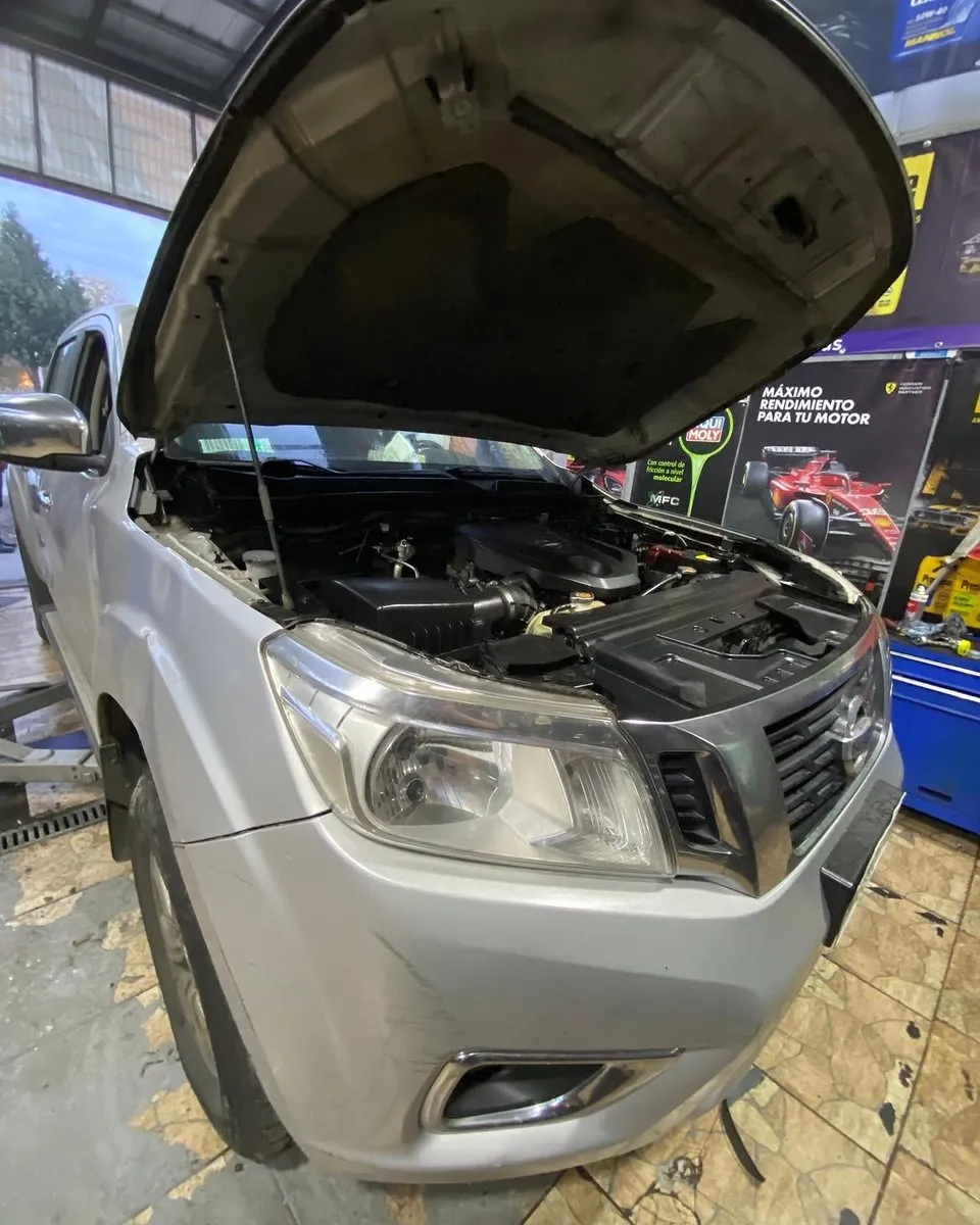 Camioneta Nissan Navara gris con el capó abierto en el taller