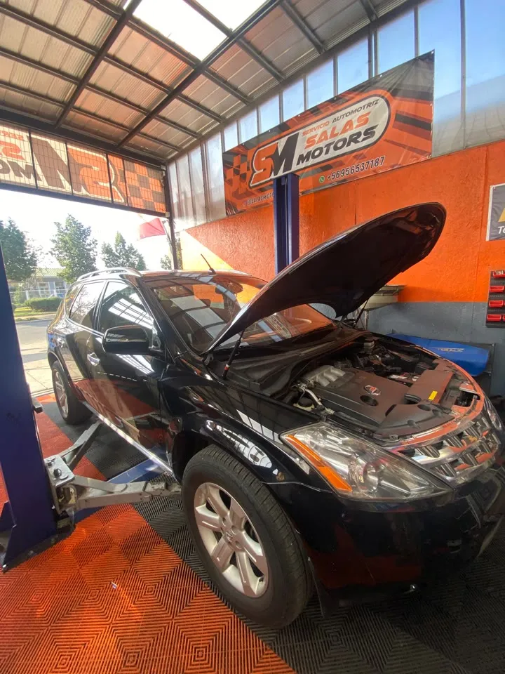 Nissan Murano negro con el capó abierto en un elevador del taller