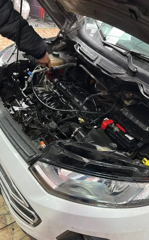 Motor de la Ford Ecosport blanca con el capó abierto, en revisión
