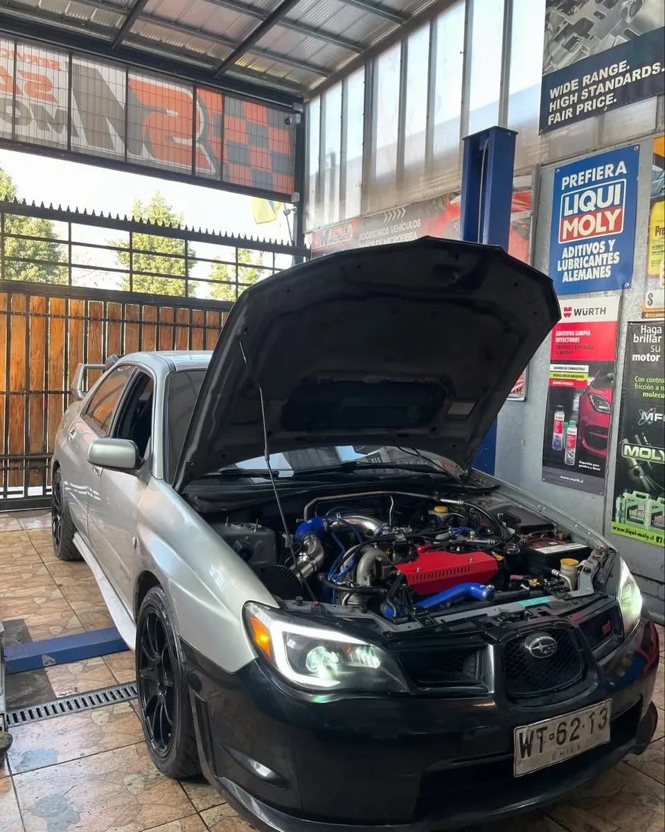 Subaru plateado con el capó abierto en el taller